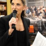 Anna Maria Pellegrino, primo piano con microfono e fogli nelle mani, mentre fa la conduttrice, speaker